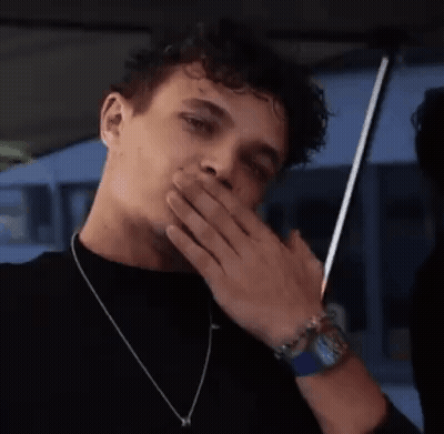 A Man With Curly Hair Is Covering His Mouth With His Hand . GIF