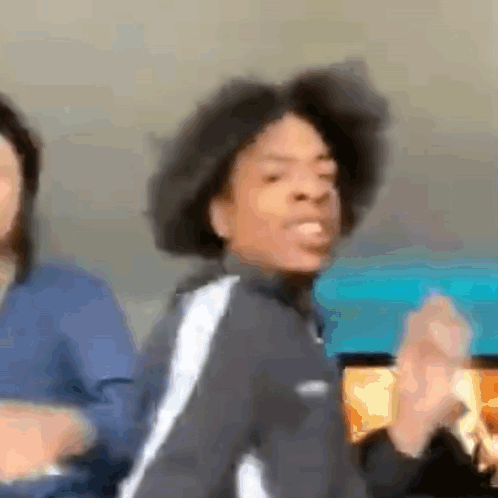 A Man With Curly Hair Is Dancing In A Blurry Photo While A Woman Looks On . GIF