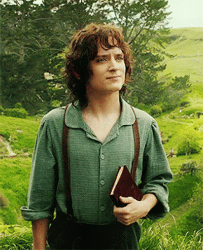 A Man With Curly Hair Is Holding A Book In A Field GIF