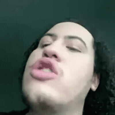 A Man With Curly Hair Is Making A Funny Face With His Eyes Closed And His Mouth Open . GIF