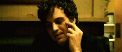 A Man With Curly Hair Is Scratching His Face With His Finger . GIF