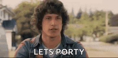 A Man With Curly Hair Is Sitting In A Park With The Words `` Lets Porty '' Written On His Face . GIF