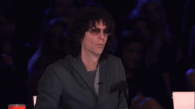 A Man With Curly Hair Is Sitting In Front Of A Microphone With His Mouth Open GIF