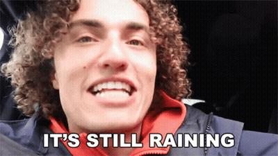 A Man With Curly Hair Is Smiling With The Words It 'S Still Raining Below Him GIF