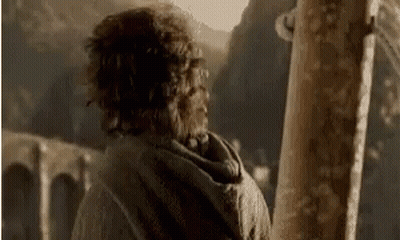 A Man With Curly Hair Is Standing In Front Of A Wooden Post . GIF