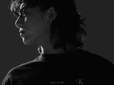 A Man With Curly Hair Is Wearing A Black Shirt That Says Calvin Klein Jeans GIF