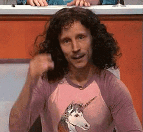 A Man With Curly Hair Is Wearing A Pink Shirt With A Unicorn On It . GIF