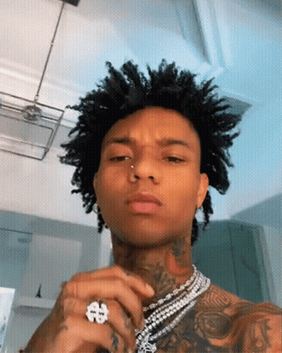 A Man With Curly Hair Is Wearing A Ring And A Necklace . GIF