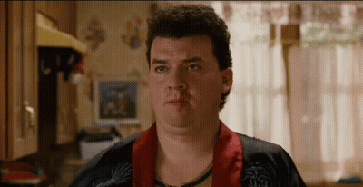 A Man With Curly Hair Is Wearing A Robe And Looking At The Camera GIF