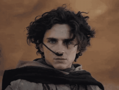 A Man With Curly Hair Is Wearing A Scarf Around His Neck And A Headset On His Nose . GIF