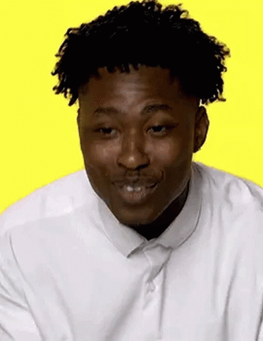 A Man With Curly Hair Is Wearing A White Shirt And Tie And Is Smiling . GIF