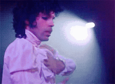 A Man With Curly Hair Is Wearing A White Shirt With Ruffles On The Sleeves GIF