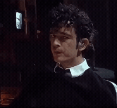A Man With Curly Hair Is Wearing Ear Buds GIF