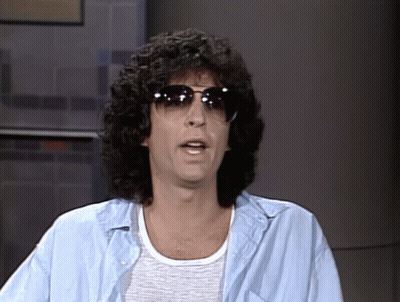 A Man With Curly Hair Is Wearing Sunglasses And A Light Blue Shirt GIF