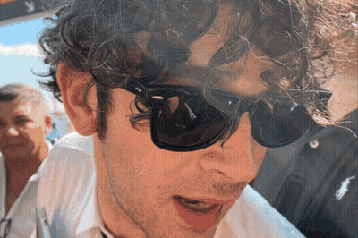 A Man With Curly Hair Is Wearing Sunglasses And A White Shirt GIF