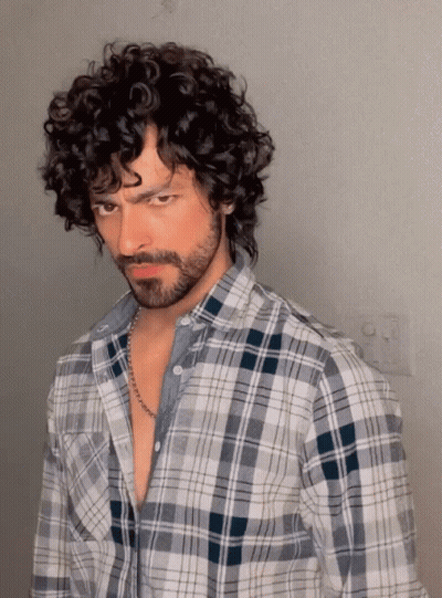 A Man With Curly Hair Wearing A Plaid Shirt GIF
