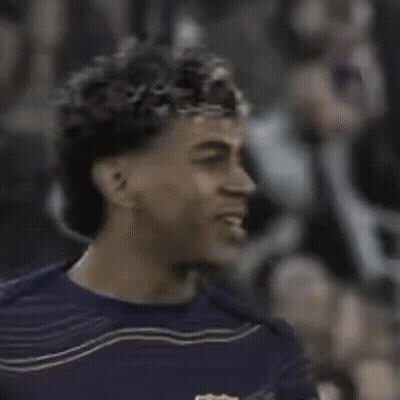 A Man With Curly Hair Wearing A Purple Shirt Is Smiling GIF