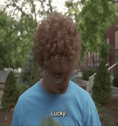 A Man With Curly Hair Wearing Glasses And A Blue Shirt Says Lucky GIF