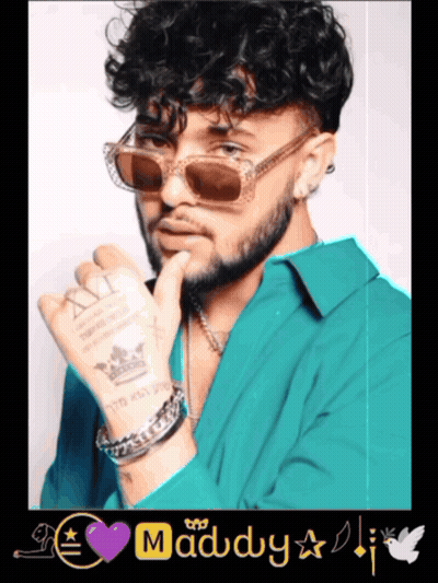 A Man With Curly Hair Wearing Sunglasses And A Purple Heart With The Word Maddy On It GIF
