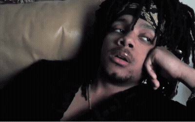 A Man With Dreadlocks And A Bandana On His Head Is Laying On A Couch GIF