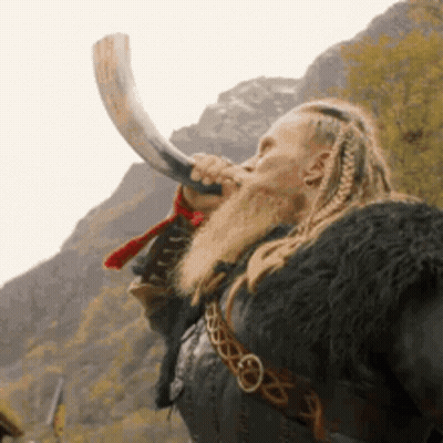 A Man With Dreadlocks And A Beard Is Blowing A Horn . GIF