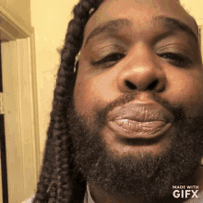 A Man With Dreadlocks And A Beard Is Blowing A Kiss At The Camera . GIF