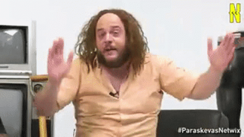 A Man With Dreadlocks And A Beard Is Sitting In Front Of A Television . GIF