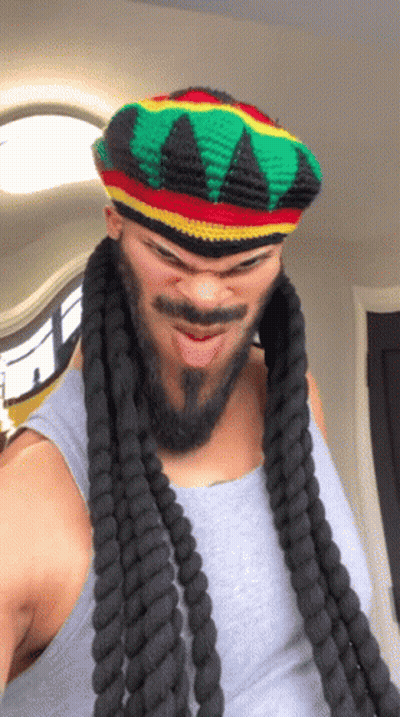 A Man With Dreadlocks And A Beard Wearing A Hat GIF