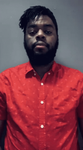 A Man With Dreadlocks And A Beard Wearing A Red Shirt GIF