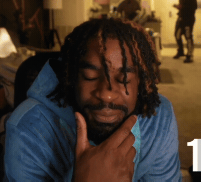 A Man With Dreadlocks And A Beard Wears A Blue Shirt GIF