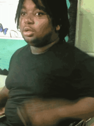 A Man With Dreadlocks And A Black Shirt Is Sitting In Front Of A Window With Butterflies On It GIF