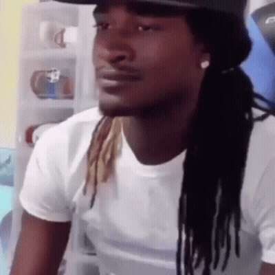 A Man With Dreadlocks And A Hat Is Wearing A White Shirt And A Hat . GIF