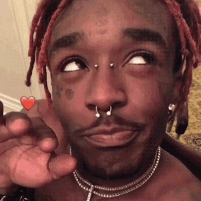 A Man With Dreadlocks And A Nose Ring Is Holding A Heart Shaped Candy In His Hand . GIF