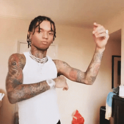 A Man With Dreadlocks And Tattoos Is Wearing A White Tank Top And Dancing . GIF