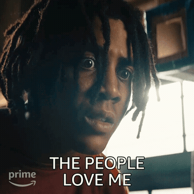 A Man With Dreadlocks Has The Words " The People Love Me " Above His Head GIF