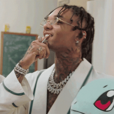 A Man With Dreadlocks Is Brushing His Teeth While Wearing Glasses GIF