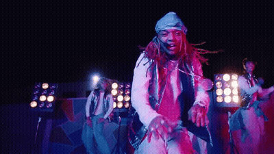 A Man With Dreadlocks Is Dancing On A Stage In Front Of A Crowd . GIF
