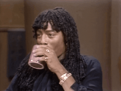 A Man With Dreadlocks Is Holding A Cup Of Coffee In His Hand . GIF