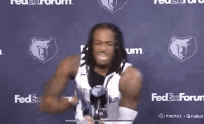 A Man With Dreadlocks Is Holding A Yellow Object In Front Of A Fedex Sign . GIF