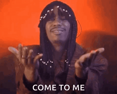 A Man With Dreadlocks Is Making A Come To Me Gesture With His Hands In The Air . GIF