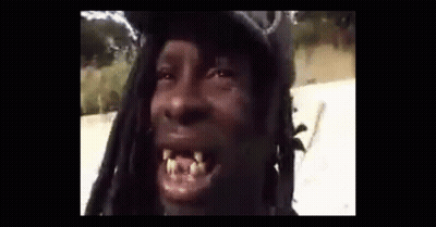 A Man With Dreadlocks Is Making A Funny Face While Wearing A Hat . GIF