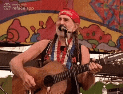 A Man With Dreadlocks Is Playing A Guitar And Singing Into A Microphone . GIF