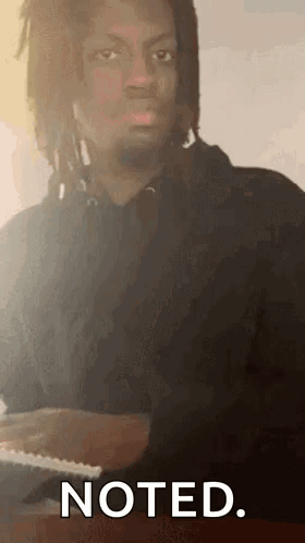 A Man With Dreadlocks Is Sitting At A Table Playing A Piano . GIF