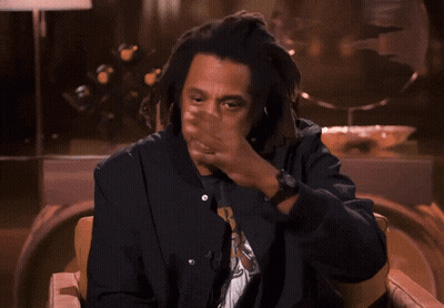 A Man With Dreadlocks Is Sitting In A Chair Giving A Thumbs Up GIF