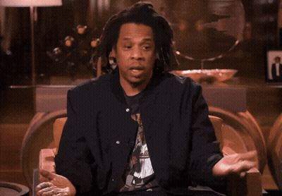 A Man With Dreadlocks Is Sitting In A Chair Talking GIF