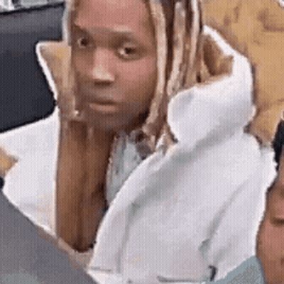 A Man With Dreadlocks Is Sitting Next To Another Man In A White Coat . GIF