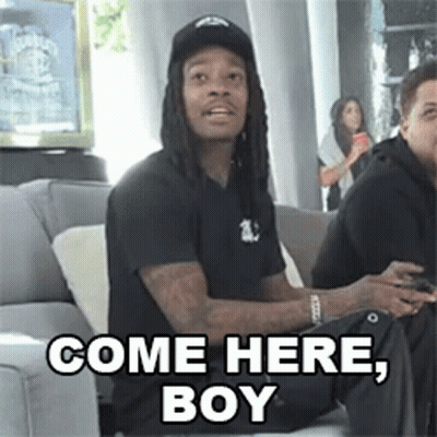 A Man With Dreadlocks Is Sitting On A Couch And Says Come Here , Boy . GIF