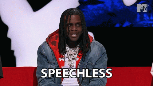 A Man With Dreadlocks Is Sitting On A Red Couch And The Word Speechless Is On The Screen In Front Of Him GIF