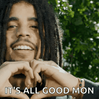 A Man With Dreadlocks Is Smiling And Making A Heart Shape With His Hands GIF