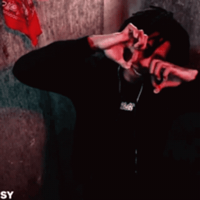 A Man With Dreadlocks Is Smiling And Making A Heart Shape With His Hands . GIF